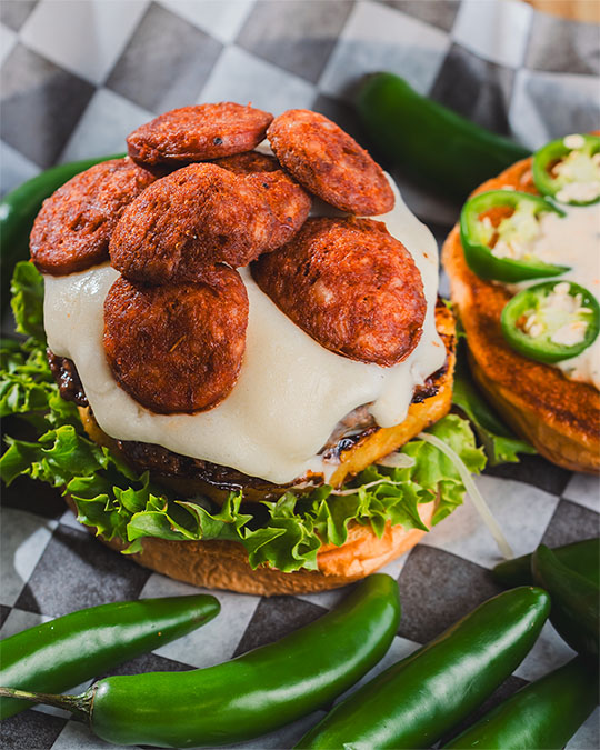 Pepperoni-topped burger with melted cheese and fresh jalapeños.