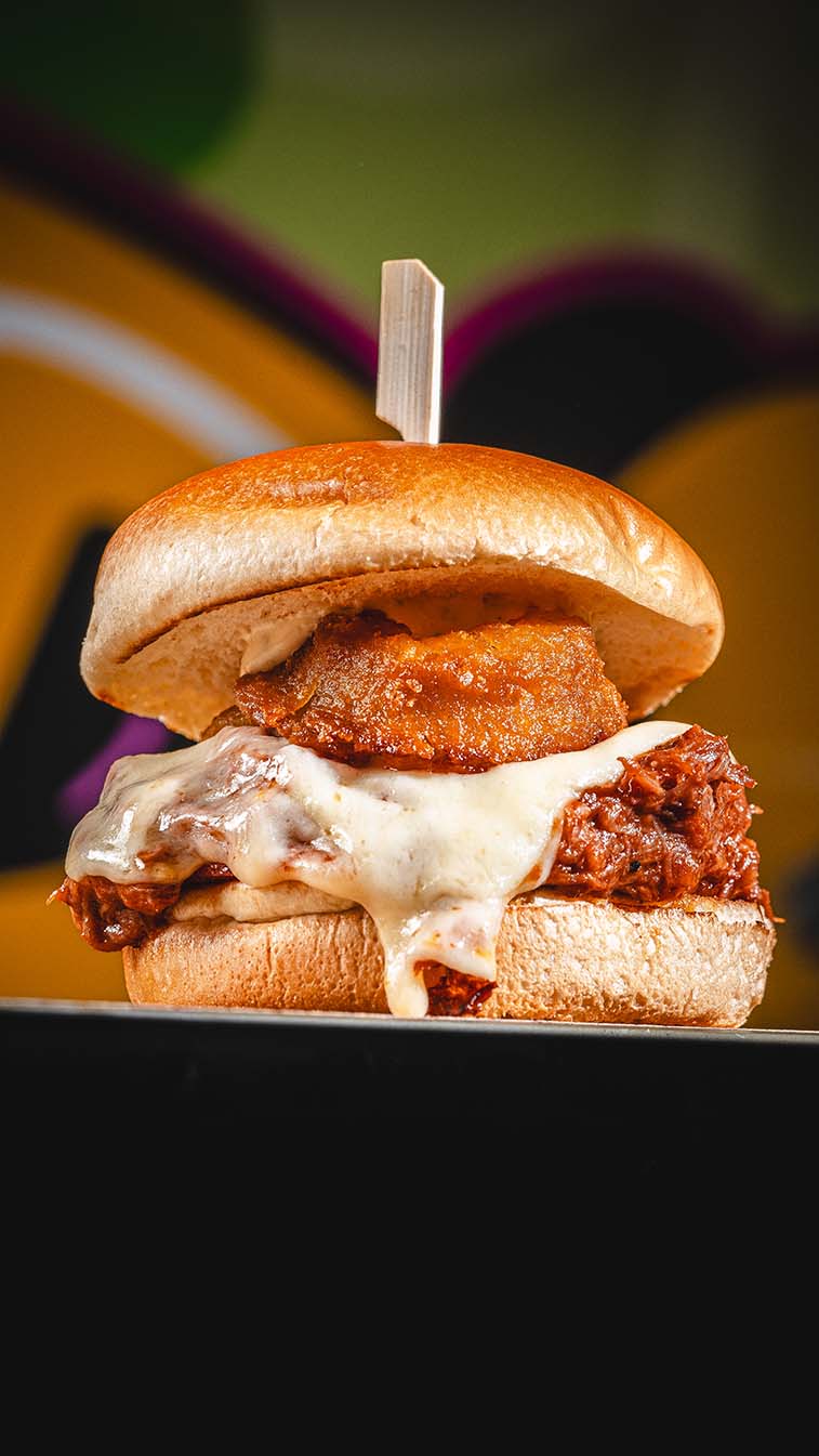 Pulled-meat burger with melted cheese and a crisp fried topping.