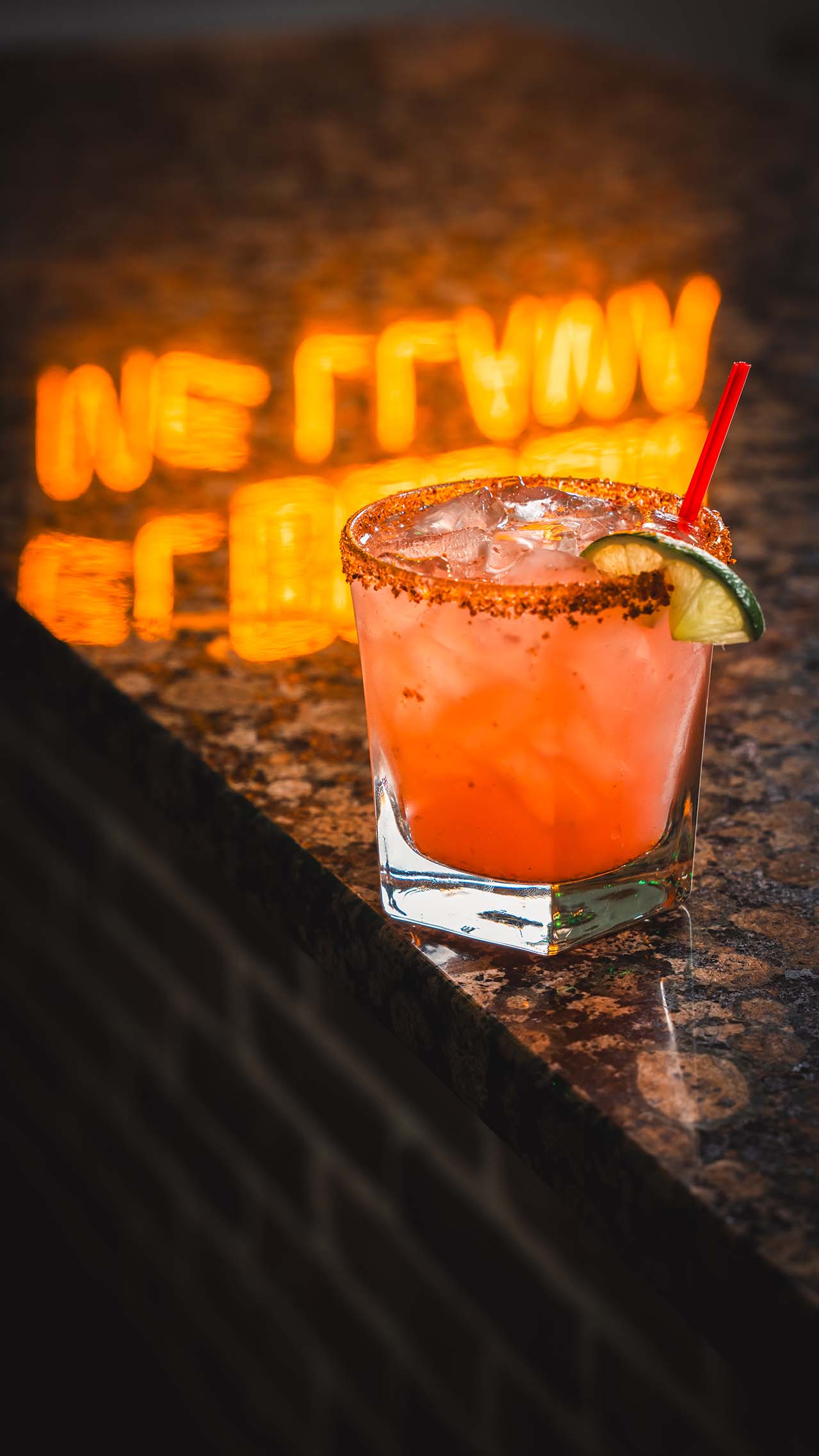 Pink signature cocktail photographed on a polished bar counter.