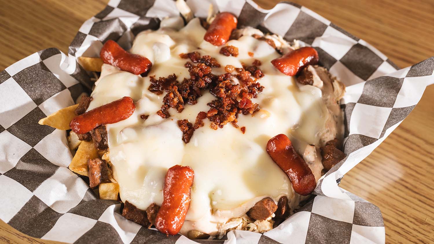 Loaded fries with mini sausages, melted cheese, bacon, and shredded meat.