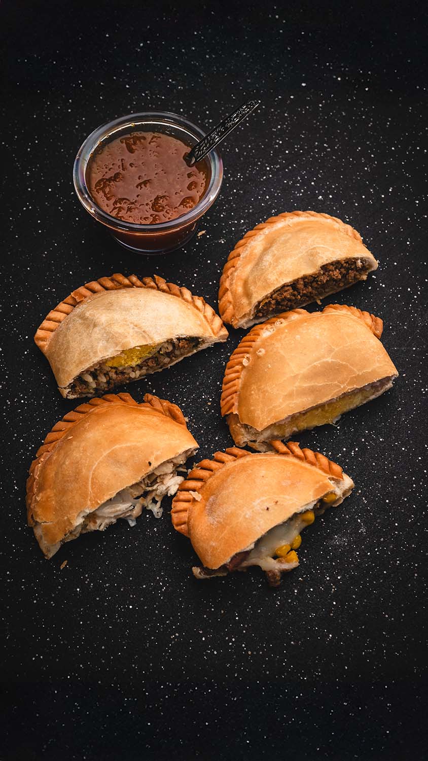 Overhead arrangement of assorted empanadas and house dipping sauce.