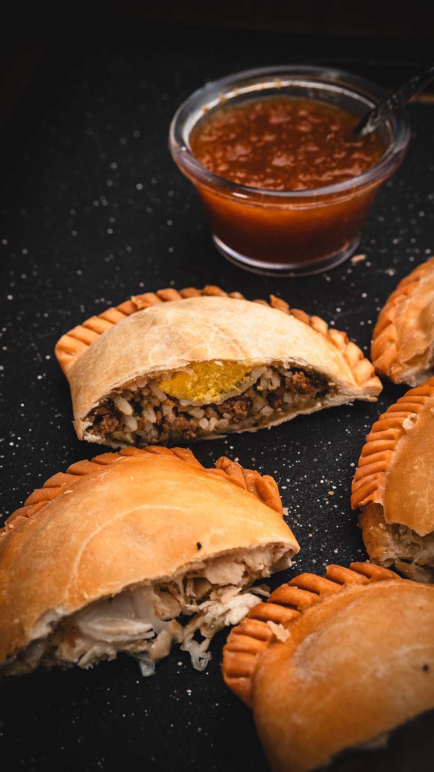 Close-up of sliced empanadas revealing savory chicken and beef fillings.