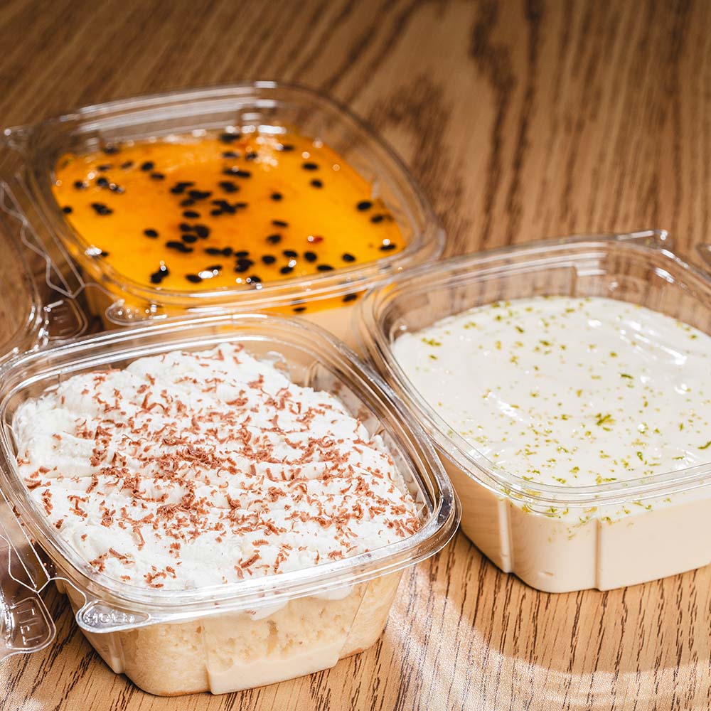 Three chilled Latin desserts photographed in clear takeaway containers.